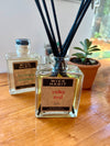 Square glass bottle of oil with black reeds